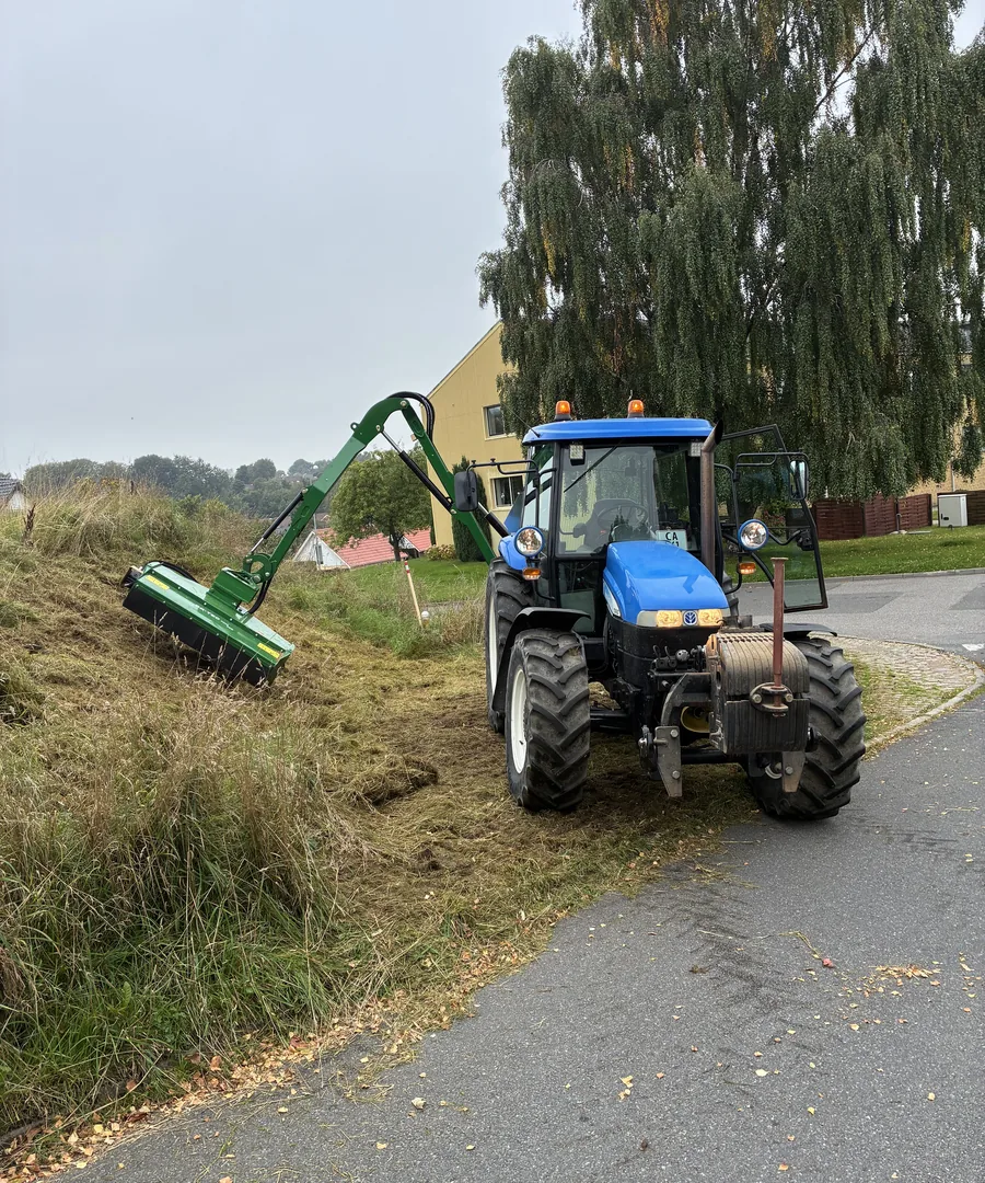 Traktor med armklipper på en nyklippet vejrabat